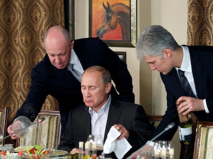 إيفجيني بريغوزين يساعد رئيس الوزراء الروسي فلاديمير بوتين خلال مأدبة عشاء مع علماء وصحفيين أجانب في مطعم شوفال بلان بمقر مجمع الفروسية خارج موسكو في 17/2/2018. - REUTERS