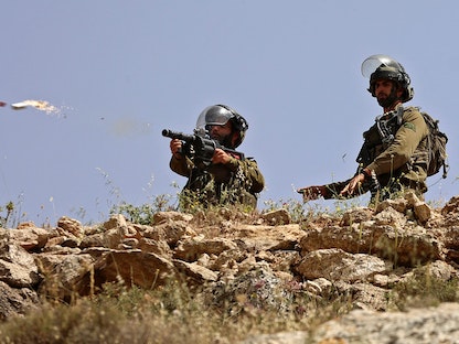 عنصران من القوات الإسرائيلية يوجهان سلاحيهما نحو متظاهرين فلسطينيين في بيت دجن شرق نابلس بالضفة الغربية المحتلة- 29 أبريل 2022  - AFP