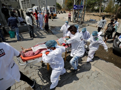عاملون صحيون ينقلون مريضاً مصاباً بفيروس كورونا إلى إحدى مستشفيات أحمد أباد في الهند - 14 أبريل 2021 - REUTERS