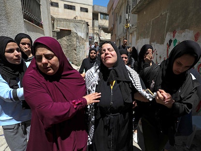 والدة الشاب الفلسطيني أحمد جميل فهد (منتصف الصورة) خلال تشييع جنازته في مخيم الأمعري للاجئين بالقرب من رام الله بالضفة الغربية، 25 مايو 2021.
 - AFP