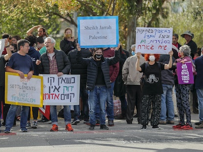 نشطاء يرفعون لافتات خلال مظاهرة ضد عمليات الاستيطان الإسرائيلي في حي الشيخ جراح في القدس- 9 أبريل 2021 - AFP