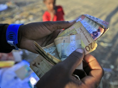 لاجئ إثيوبي فر من القتال في منطقة تيغراي يحصي أموالاً سودانية في مركز استقبال حدودي بولاية القضارف شرقي السودان- 26 نوفمبر 2020 - AFP