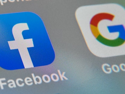 شعارا تطبيقي غوغل وفيسبوك على شاشة جهاز لوحي في مدينة ليل، فرنسا - AFP