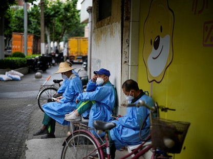 عمال يردتون ملابس وأقنعة للوقاية من فيروس كورونا في مدينة شنغهاي الصينية وسط قيود الإغلاق - 28 مايو 2022 - REUTERS
