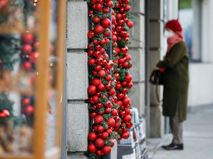 ألمانية ترتدي كمامة وتتطلع على واجهة إحدى المحال المزينة باحتفالات أعياد الميلاد في مدينة ميونخ - REUTERS