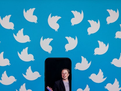 شعار تويتر خلف هاتف يظهر داخله صورة للملياردير الأميركي إيلون ماسك. 19 ديسمبر 2022. - AFP