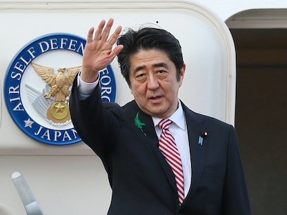 رئيس الوزراء الياباني الراحل شينزو آبي يلوّح وهو يغادر إلى إندونيسيا في مطار طوكيو الدولي في طوكيو- 21 أبريل 2015 - AFP
