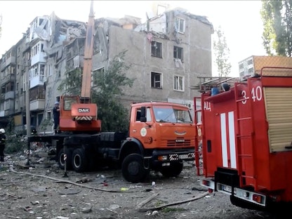 عمال الإنقاذ أمام مبنى سكني تعرض لضربة عسكرية روسية في ميكولايف الأوكرانية - 29 يونيو 2022  - REUTERS