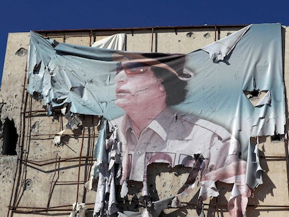 لافتة ممزقة تظهر معمر القذافي شوهدت على مبنى خلال اشتباكات بين مقاتلين مناهضين للقذافي وقوات القذافي في سرت 12 أكتوبر 2011. - REUTERS