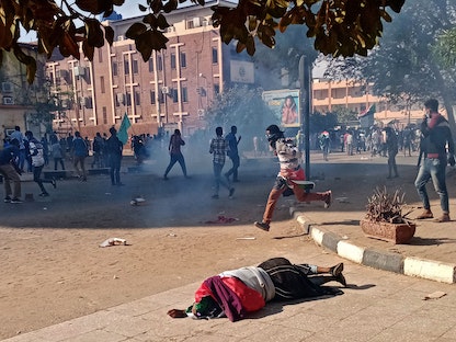 متظاهر سوداني سقط مصاباً على الرصيف بعدما أطلقت قوات الأمن الغاز المسيل للدموع خلال مظاهرة في الخرطوم، 19 ديسمبر 2021 - AFP