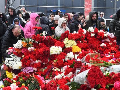 أشخاص يضعون الزهور على نصب تذكاري مؤقت أمام قاعة الحفلات في "مركز كروكوس" في ضاحية كراسنوجورسك بموسكو. 24 مارس 2024 - AFP