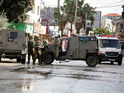 جنود إسرائيليون وآليات عسكرية أمام سيارة إسعاف فلسطينية خلال مداهمات واقتحامات لمدينة ومخيم جنين بالضفة الغربية. 13 ديسمبر 2023 - Reuters