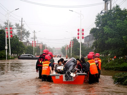 فريق إنقاذ يجلي قرويين تقطعت بهم السبل جرّاء مياه الفيضانات في مدينة شوتشانغ الصينية، 21 يوليو 2021 - REUTERS