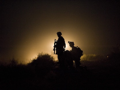 عناصر من البحرية الأميركية يحرسون خلال البحث عن مشاة البحرية المفقودين بعد انفجار عبوة ناسفة بدائية في منطقة جارمسير في ولاية هلمند الأفغانية - AFP