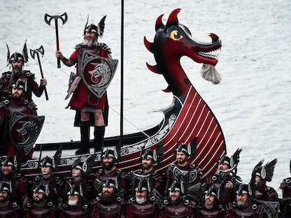 أعضاء فرقة "Up Helly Aa" يلتقطون صوراً مع سفينتهم Viking galley في جزر شتلاند باسكتلندا. 31 يناير 2023  - AFP