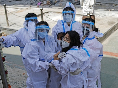 سيدات يرتدين معدات الوقاية الشخصية (PPE) عند وداع متوفى، بسبب فيروس كورونا في محرقة جثث في العاصمة الهندية نيودلهي - REUTERS
