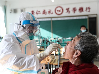 عامل طبي يأخذ مسحة من أحد السكان لاختبار فيروس كورونا في مدينة شنيانغ بمقاطعة لياونينغ، شمال شرقي الصين. 31 ديسمبر 2020 - AFP