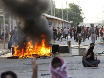 متظاهرون عراقيون يحرقون إطارات خلال احتجاجات بمدينة النجف - REUTERS