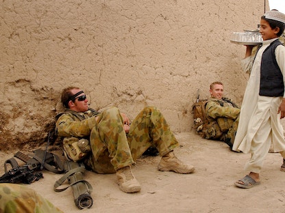 طفل أفغاني يمر أمام جنود ضمن القوات الأجنبية في أفغانستان عام 2008 - AFP