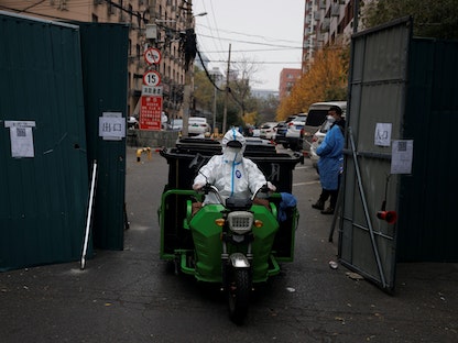 عامل وقاية من الأوبئة ينقل صناديق النفايات من مجمع سكني مغلق مع استمرار تفشي مرض فيروس كورونا (COVID-19) في العاصمة بكين، الصين - 18 نوفمبر 2022 - REUTERS