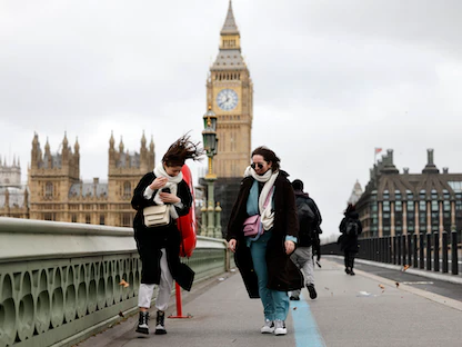 مشاة في مهب الريح عبر جسر وستمنستر بالقرب من مجلس البرلمان في وسط لندن - 18 فبراير 2022 - AFP