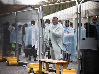 أشخاص يقفون داخل منطقة مسيجة بمركز مانستون للمهاجرين في بريطانيا. 7 نوفمبر 2022 - REUTERS