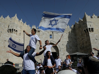 شباب إسرائيليين يلوحون بالأعلام أثناء مشاركتهم في مسيرة بمناسبة "يوم القدس" بالقرب من باب العامود في البلدة القديمة بالقدس، 2 يونيو 2021 - REUTERS