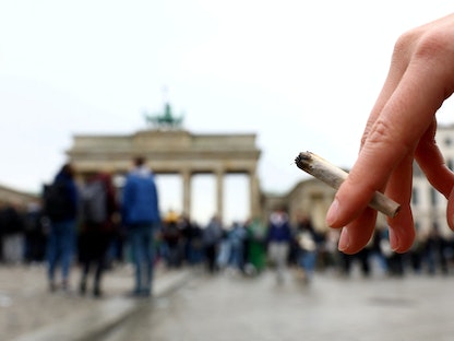 شخص يحمل سيجارة في الاحتفال باليوم العالمي  للقنب أمام بوابة براندنبورج في برلين-  20 أبريل 2022  - REUTERS