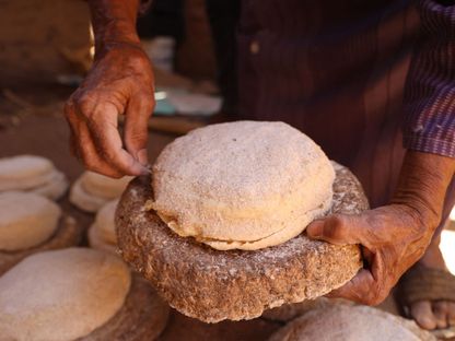 سيدة سودانية تعد الخبز في فرن من الطين بوادي حلفا في السودان. 29 أبريل 2023 - AFP