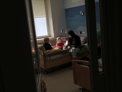 امرأة وطفلان يجلسون على سرير في عيادة الأورام التابعة للمركز الطبي المتخصص في غرب أوكرانيا . 10 مارس 2022  - REUTERS