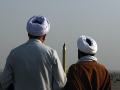 رجال دين إيرانيون ينظرون إلى صاروخ باليستي "شهاب 1" خلال إجراء تدريبات عسكرية في مكان غير معروف - AFP