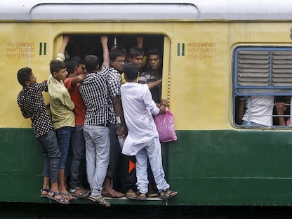 ركاب يقفون على باب مفتوح لقطار خلال ساعة الذروة الصباحية في كولكاتا بالهند - 31 يوليو 2015 - REUTERS