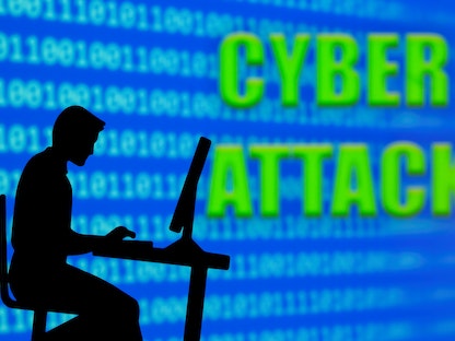 صورة توضيحية لرجل يعمل على الكمبيوتر بجانب جملة "هجوم إلكتروني" - REUTERS