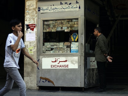 لبنانيان يمرّان قرب مكتب صرافة مغلق في بيروت - 29 نوفمبر 2019 - AFP