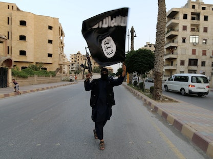 عنصر في "داعش" يُلوح بعلم التنظيم بعد السيطرة على مدينة الرقة السورية- 29 يونيو 2014 - REUTERS