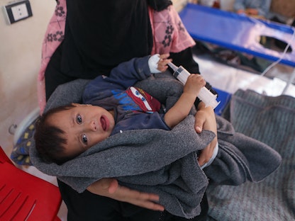 امرأة تحمل طفلها أثناء العلاج في مركز طبي لحالات الكوليرا في بلدة دركوش السورية، على مشارف محافظة إدلب، 22 أكتوبر 202 - AFP
