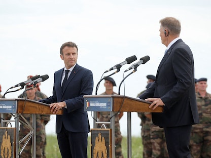 الرئيس الفرنسي إيمانويل ماكرون ونظيره الروماني كلاوس يوهانيس يتحدثان خلال زيارتهما لقاعدة جوية قرب مدينة كونستانتا الرومانية- 15 يونيو 2022 - AFP