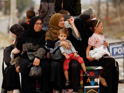 فلسطينيون فارون من شمال غزة يركبون في الجزء الخلفي من شاحنة أثناء تحركهم جنوباً وسط حرب إسرائيل على غزة. 12 نوفمبر 2023. - Reuters