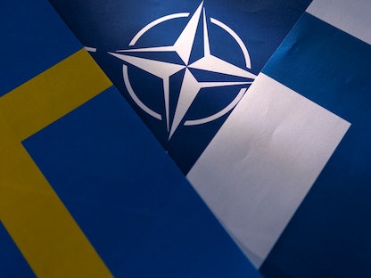 علما فنلندا والسويد مع خلفية لشعار حلف الناتو - REUTERS