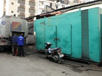 رجال يقومون بتعبئة مولداً خاصاً يوفر الكهرباء بزيت الديزل في بيروت، لبنان في 21 يناير 2022.  - REUTERS