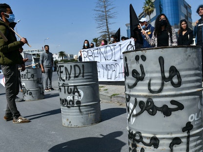 أنصار منظمات غير الحكومية يرفعون لافتة للمطالبة بإعادة نفايات منزلية مصدرة بشكل غير قانوني من إيطاليا، في مدينة سوسة، تونس. 28 مارس 2021. - AFP