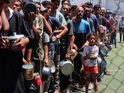 فلسطينيون يتجمعون لتلقي الطعام من مطبخ خيري في النصيرات وسط قطاع غزة. 20 يوليو 2025 - REUTERS