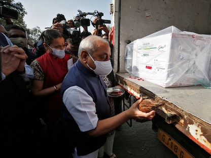 نيتين باتيل، نائب رئيس وزراء ولاية غوجارات، يكسر ثمرة جوز الهند كجزء من طقوس محلية بعد وصول شحنة تحتوي على لقاح مضاد لكورونا يصنعه معهد سيروم في الهند. 12 يناير 2021. - REUTERS