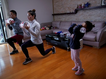 أسرة تمارس الرياضة باستخدام زجاجات المياه أثناء مشاهدة دروس لياقة بدنية عبر الإنترنت في منزلهم بشنغهاي، الصين- 25 فبراير 2020  - REUTERS
