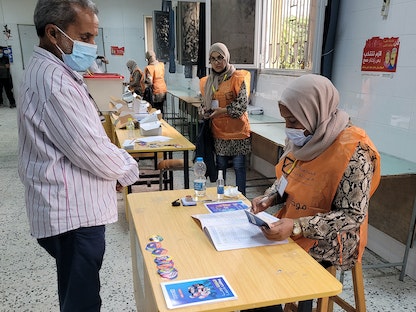 مواطن ليبي يسجل في مركز اقتراع بالعاصمة الليبية طرابلس تمهيداً للتصويت في الانتخابات المقبلة، 8 نوفمبر 2021 - AFP