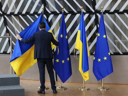 شخص يضع العلم الأوكراني بين أعلام الاتحاد الأوروبي قبل انعقاد قمة القادة الأوروبيين في العاصمة البلجيكية بروكسل. 9 فبراير 2023 - REUTERS