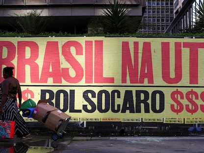 امرأة تمر أمام لافتة مكتوب عليها "البرازيل في وحدة العناية المركزة"، 8 مارس 2021 - REUTERS