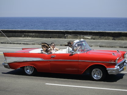سائحان في سيارة شيفروليه صُنعت في عام 1957 على جادة هافانا - 21 مايو 2013 - REUTERS