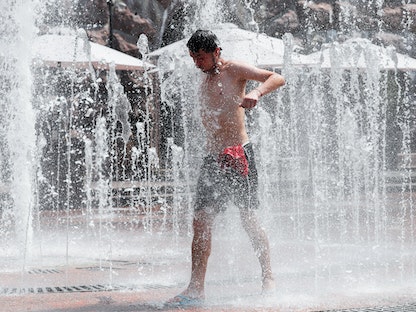 شخص يحاول تبريد جسمه للتغلب على حراراة الطقس في نافورة عامة بالعاصمة الأوكرانية كييف - 16 يوليو 2021  - REUTERS