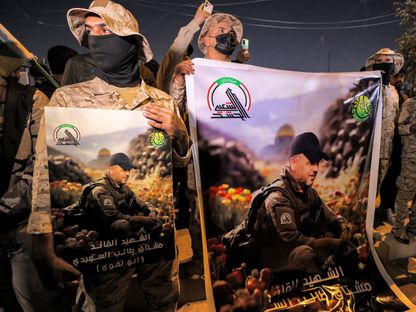 أعضاء من الحشد الشعبي يحملون صوراً لـ"أبو تقوى" الذي قُتل في ضربة أميركية. بغداد، العراق. 4 يناير 2024 - AFP